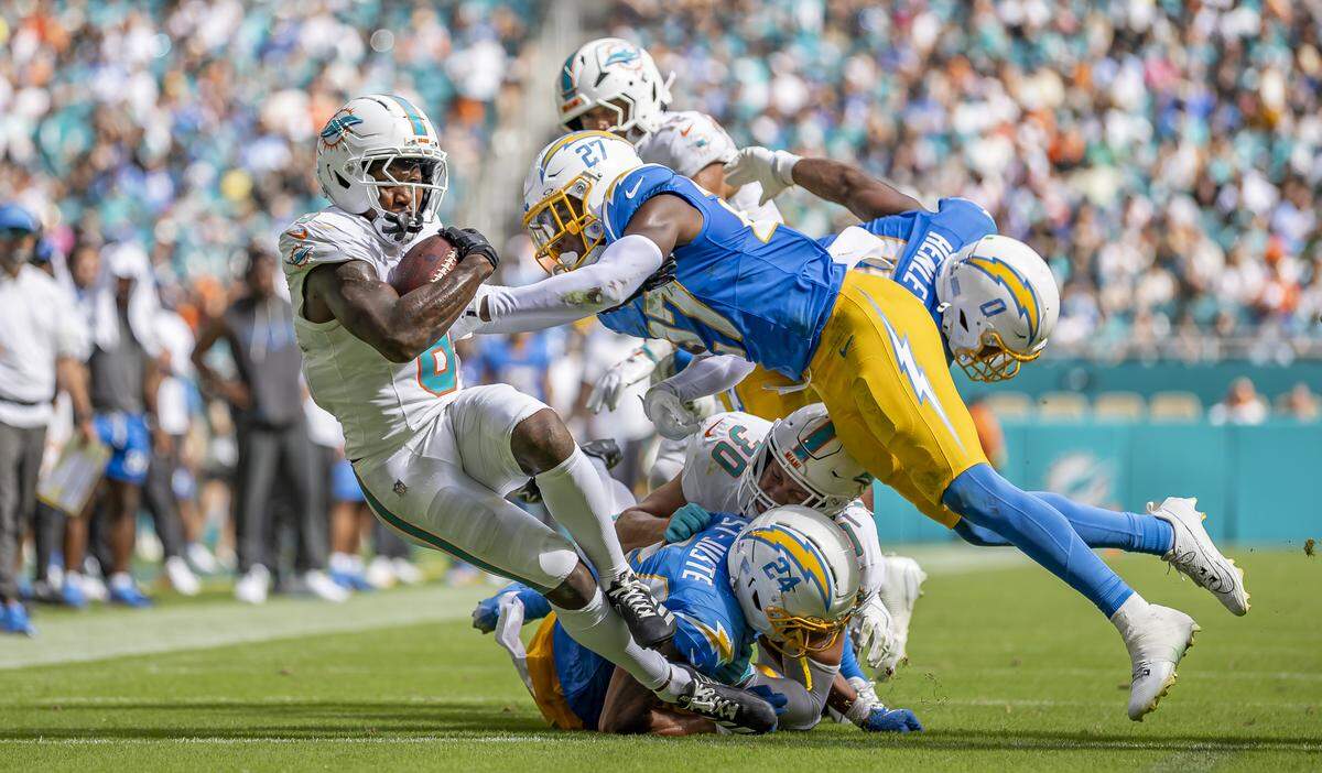 Miami Dolphins wide receiver Malik Washington (6) runs with the ball as Los Angeles Chargers cornerback Benjamin St-Juste (24) and safety R.J. Mickens (27) go for the tackle in the second half of their NFL game at Hard Rock Stadium on Sunday, Oct. 12, 2025, in Miami Gardens, Fla.