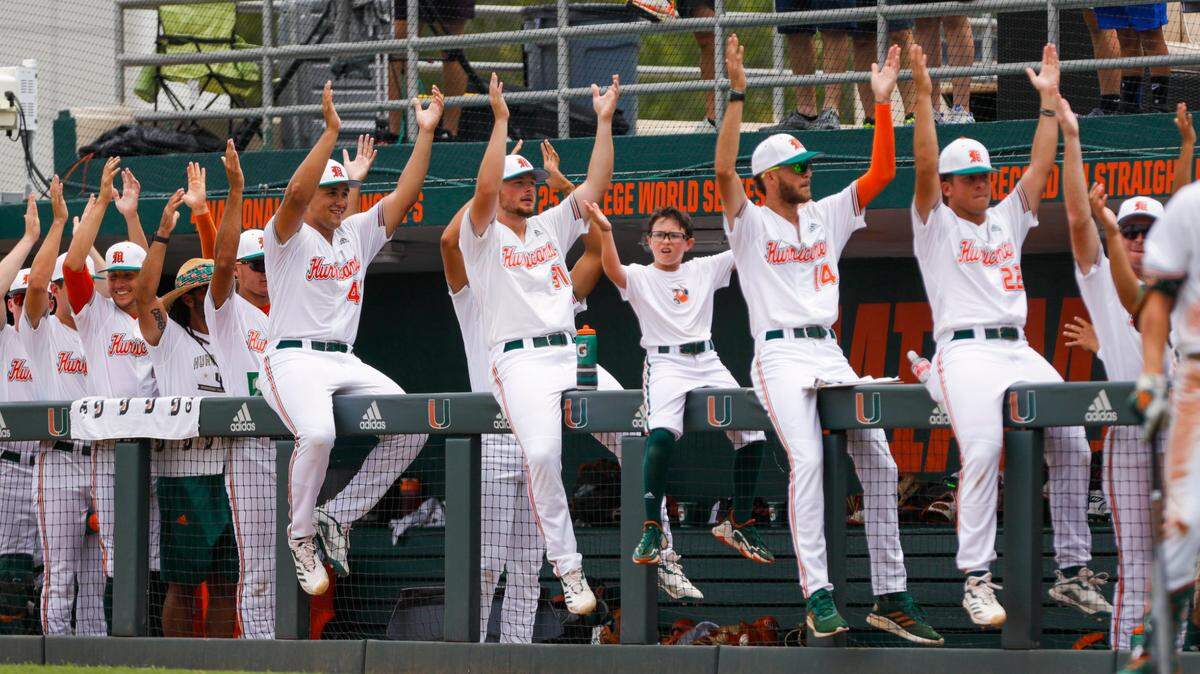 Miami Hurricanes baseball players dance from inside the dugout during the game against Notre Dame at Alex Rodriguez Park at Mark Light Field in Coral Gables, Florida on Saturday, May 21, 2022.