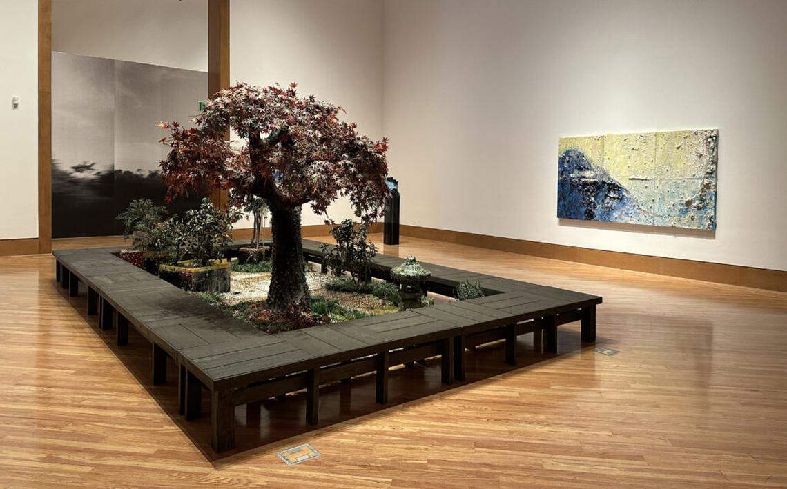 Exhibition view of monumental sculpture “Endless Autumn” portraying a Japanese garden in jeweled artifice by Cristina Lei Rodriguez. Richly textured landscape painting “Traversing Boundaries” on wall and photo “I sit as a passenger (on this road)” by Amanda Bradley.
