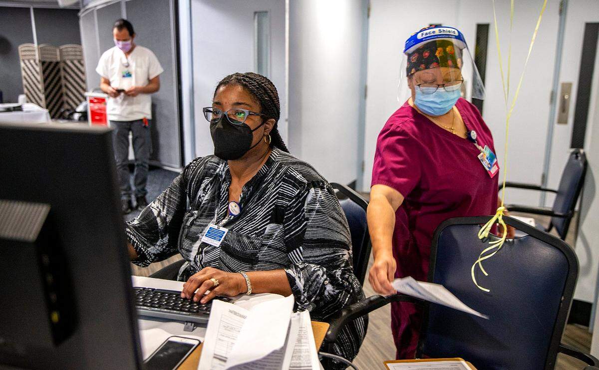 Lantaya Chayten, left, an outpatient coordinator, and nurse Lynnette Lee, check in some employees getting vaccinated with the Moderna COVID-19 vaccine at the Miami Jewish Health on Aug. 19, 2021.