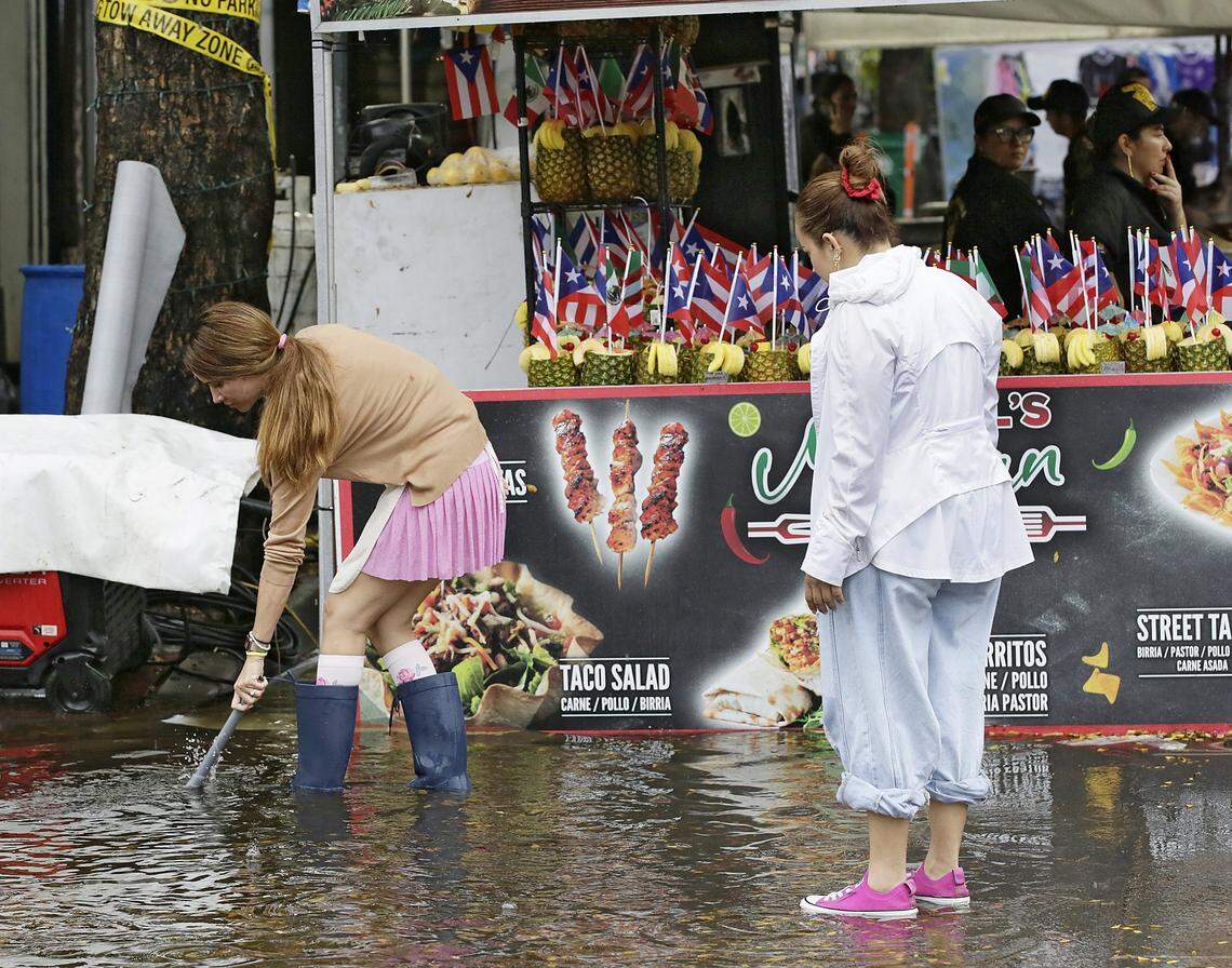 The vendors try to unclog the rain drain on SW 8 street in Little Havana during Calle Ocho festival on Sunday, March 15, 2026. Andrew Uloza / for Miami Herald
