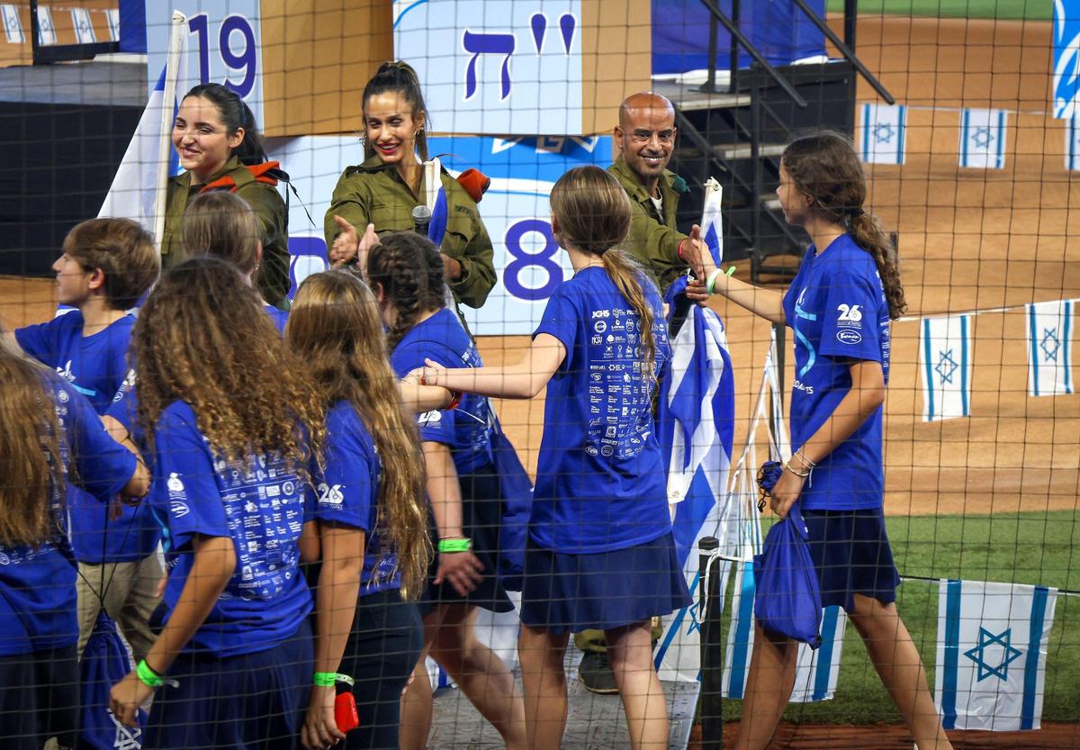 Israeli Defense Forces soldiers Natalia Levi, left, Moran Elbaz, center, and Netanel Cohen, right, greet students and adults as they parade into the ballpark on Wednesday, April 26, 2023 for Israeli Independence Day festivities in Miami.