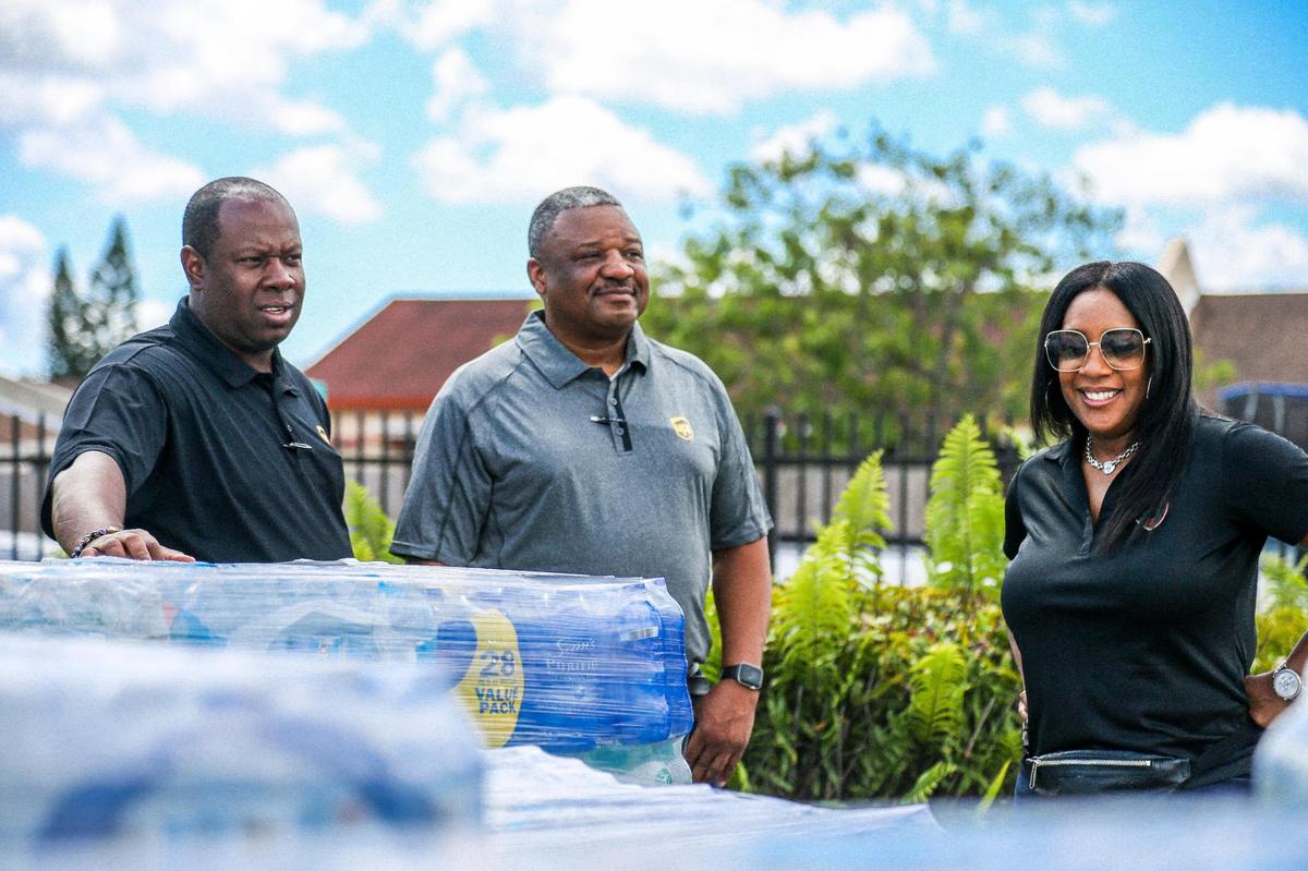 From left, Miami Gardens Vice Mayor Reggie Leon, UPS business manager Andre Gooden and Orange Blossom Classic Executive Director Kendra Bulluck, wait for a UPS truck to load pallets of water cases for people in Jackson, Miss., at Betty T. Ferguson Recreational Complex park in Miami Gardens, Florida, Monday, Sept. 12. 2022.