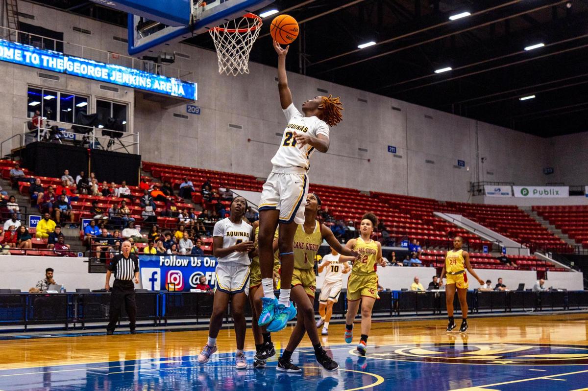 St. Thomas Aquinas’ Nyla McFadden (21) lays up the ball after driving past Lake Gibson defender Taniya Brown (1) during the Class 6A Florida High School State Girl’s basketball Semifinal at RP Funding Center in Lakeland, Florida, on Thursday, February 23, 2023.