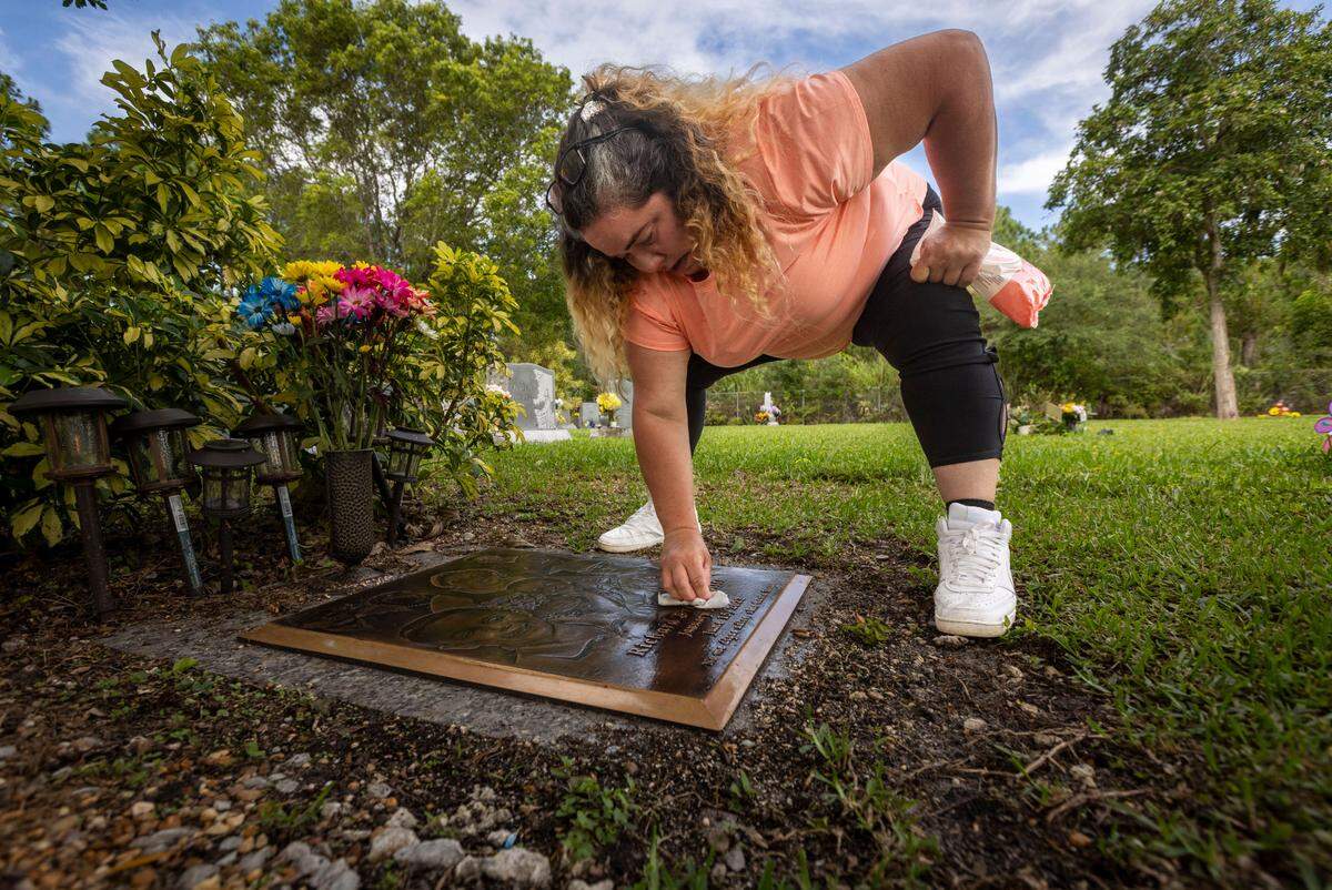 Gamaly Hollis cleans her son Richard’s grave during a visit in June.