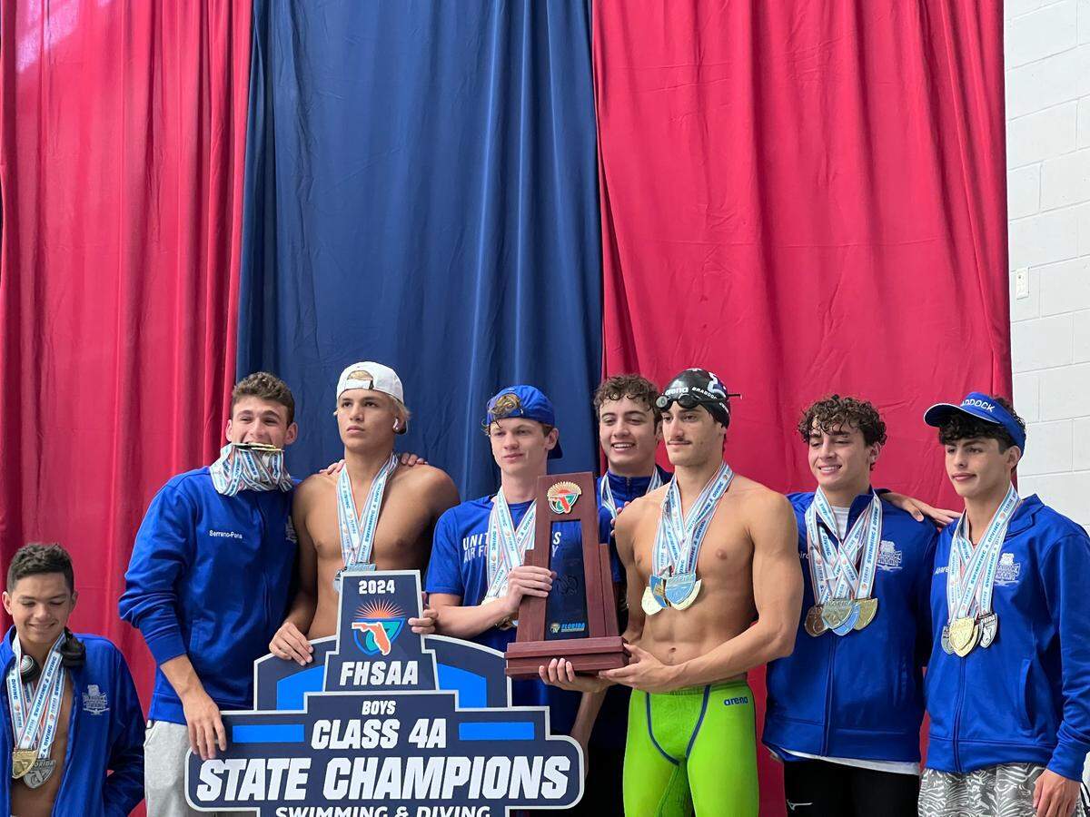 Braddock’s boys swimmers celebrate on the medal stand on Saturday night in Ocala after winning the school’s first ever state championship.