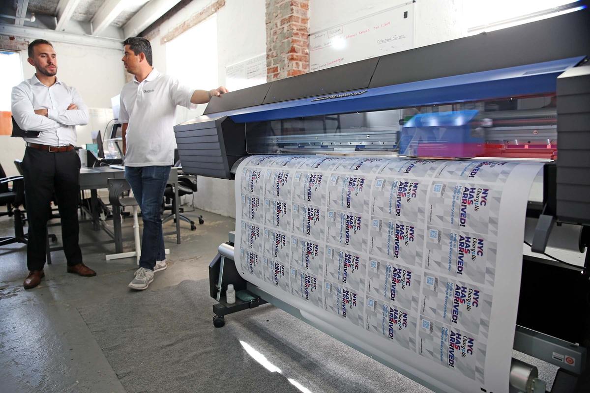 Gustavo Herdocia and Stefano Nardi print labels for the chargers in their office in Miami, Florida, Tuesday, July, 9, 2019. Chargello provides venues with cellphone chargers and also uses the devices for marketing.