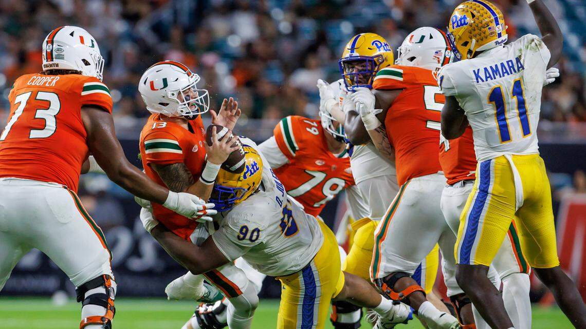 Miami Hurricanes quarterback Jake Garcia (13) is being sacked by Pittsburgh Panthers defensive lineman Deandre Jules (90) during the second quarter of an ACC conference football game at Hard Rock Stadium on Saturday, November 26, 2022 in Miami Gardens, Florida.