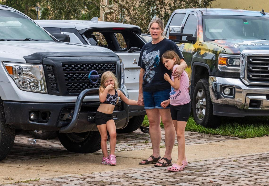 Melissa Cline and her two daughters stand in front of their house at the Portofino Shores Community in St. Lucie County, Friday, Oct. 11, 2024, Their house is among the many that suffered damages by a pair of tornadoes that tore through the neighborhood hours before Hurricane Milton made landfall on Florida’s west coast on Wednesday, Oct. 9, 2024.