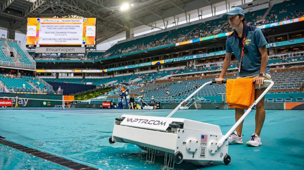 A crew member works to dry the court as a rain delay postpones the Miami Open tennis tournament on Tuesday, March 25, 2025, at Hard Rock Stadium in Miami Gardens, Fla.