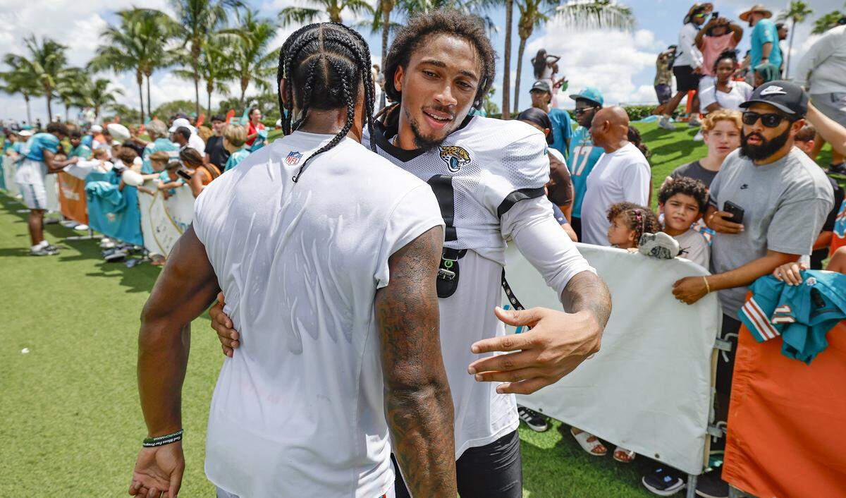 Jacksonville Jaguars cornerback Keni-H Lovely, right, greets Miami Dolphins wide receiver Dee Eskridge, left, in front of fans seeking autographs after a joint NFL football practice at the Miami Dolphins Training Camp in Miami Gardens.