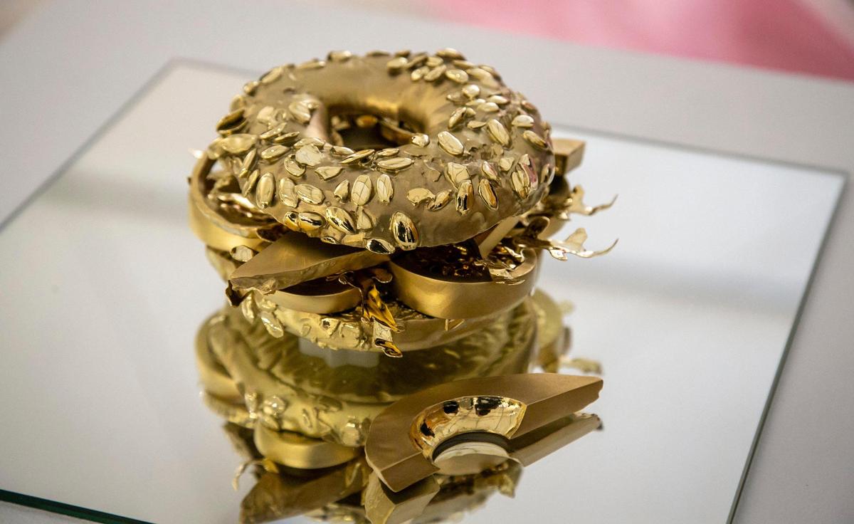 A solid gold cast of an avocado toast titled “Who wants to live forever?” by artist Tim Bengel at Art Miami located at One Herald Plaza.