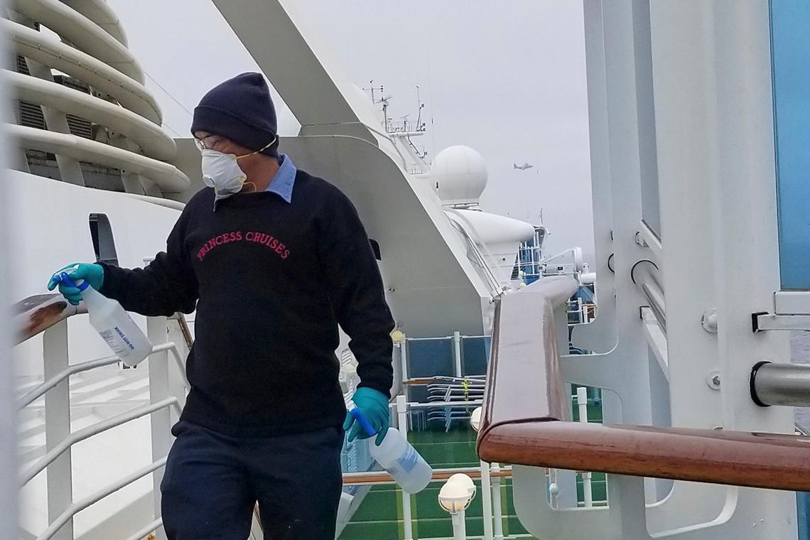 A cruise ship worker cleans a railing on the Grand Princess Thursday, March 5, 2020, off the California coast. Scrambling to keep the coronavirus at bay, officials ordered the cruise ship with about 3,500 people aboard to stay back from the California coast until passengers and crew were tested.