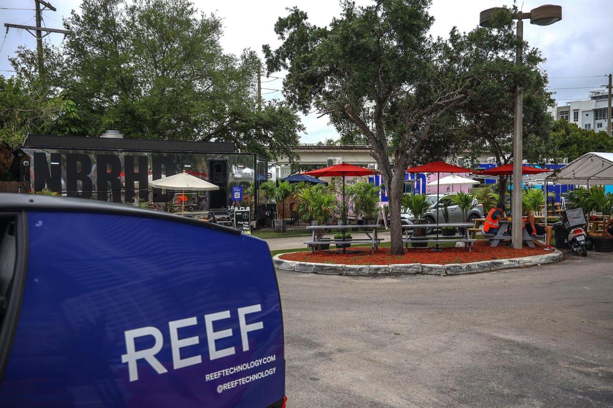 Conductores de reparto y robots recogen comida de las cocinas móviles instaladas en un estacionamiento de Brickell, el martes 20 de abril de 2021. Una empresa llamada REEF quiere poner en marcha más cocinas de este tipo en terrenos baldíos de toda la ciudad.