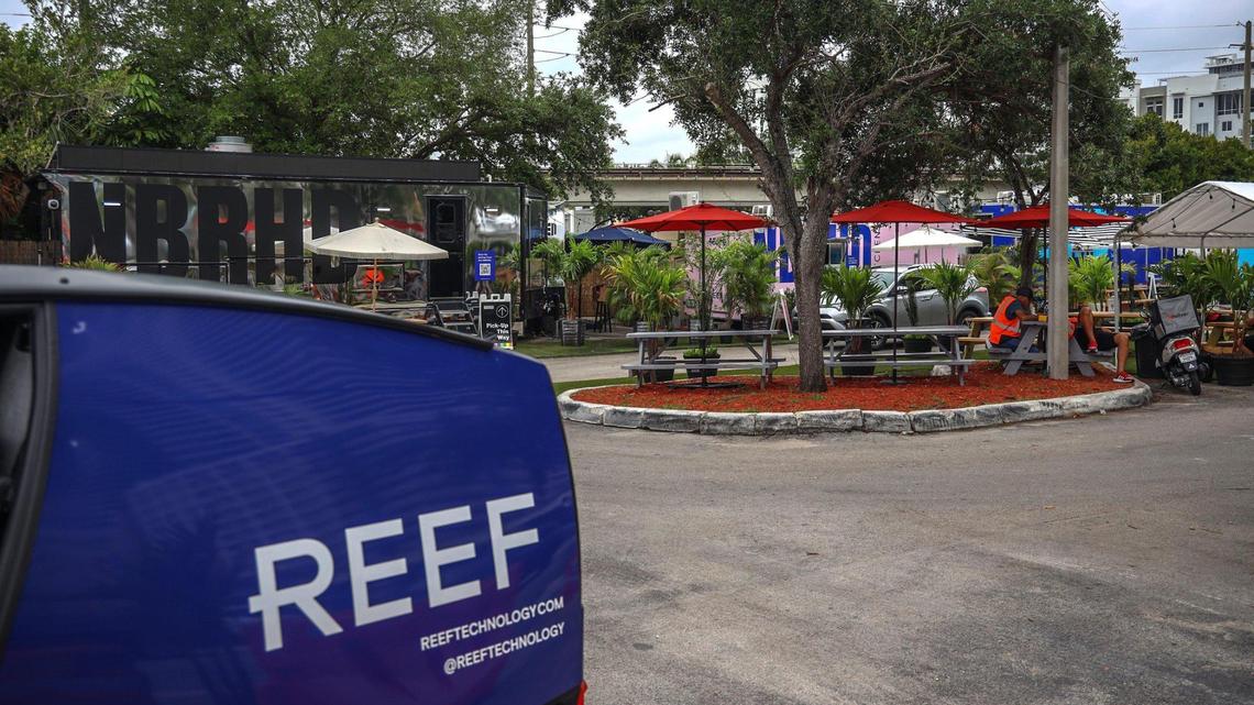 Delivery drivers and robots pick up food from mobile kitchens set up in a Brickell parking lot on Tuesday, April 20, 2021. A company called REEF wants to operate more such kitchens on vacant land across the city.