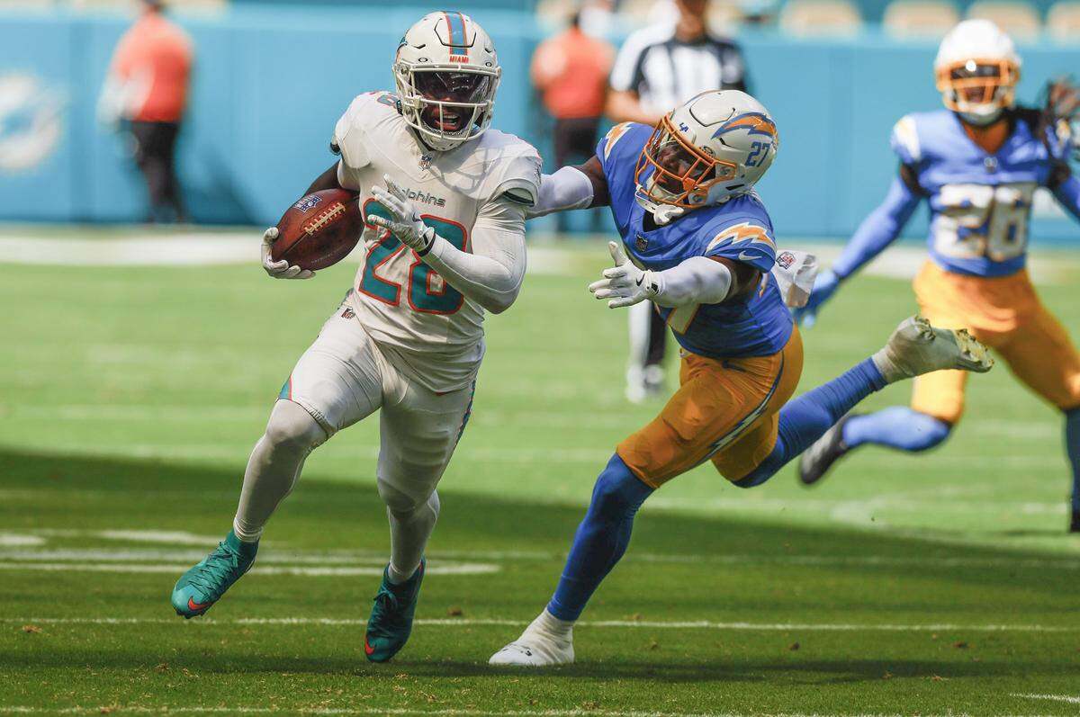 Miami Dolphins running back De'Von Achane (28) runs into score as Los Angeles Chargers safety R.J. Mickens (27) gives chase in the first half during their NFL football game at Hard Rock Stadium in Miami Gardens, FL, on Sunday, October 12, 2025. 