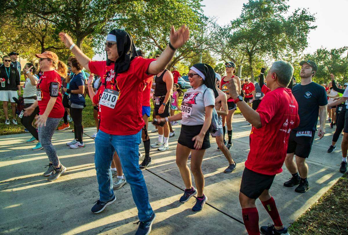 Runners Harvey Samowitz (front) and Rebecca Lee wear nun’s habit on Saturday April 9, 2022, as they warm up for the Barry University 5K/8K Nun Run that is back after a pandemic prompted hiatus. The annual Barry University 5K/8K Nun Run runs through Miami Shores to honors Barry’s founders, the Adrian Dominican Sisters.