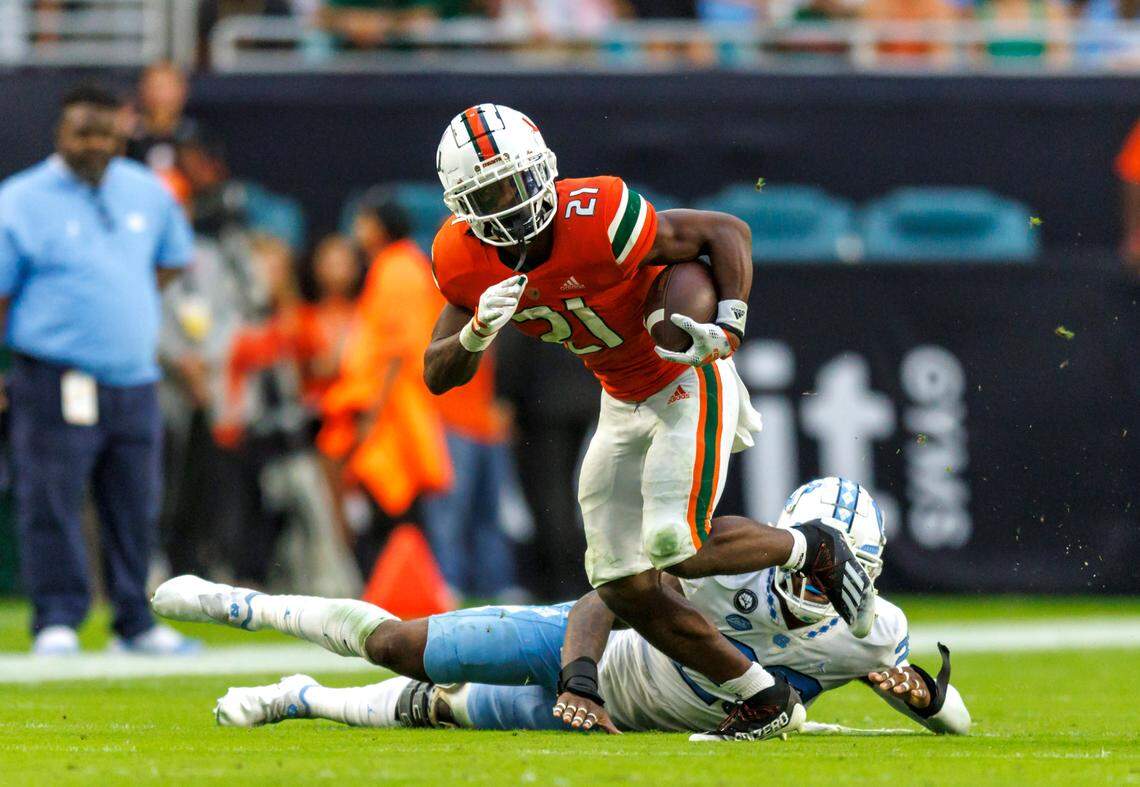 Miami Hurricanes running back Henry Parrish Jr. (21) runs with the football against North Carolina Tar Heels linebacker Power Echols (23) during the second quarter of an ACC conference football game at Hard Rock Stadium on Saturday, October 8, 2022 in Miami Gardens, Florida..