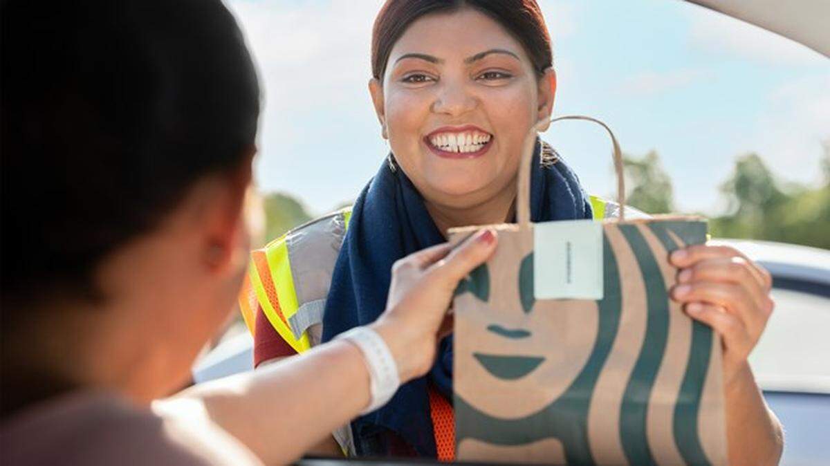 Target puso en marcha su servicio de recogida Starbucks Drive Up a nivel nacional en agosto de 2023. El servicio está disponible en la mayoría de los 35 Target de Miami. En esta imagen, una empleada entrega un pedido en el auto a un cliente. Starbucks Ketchum Communications.
