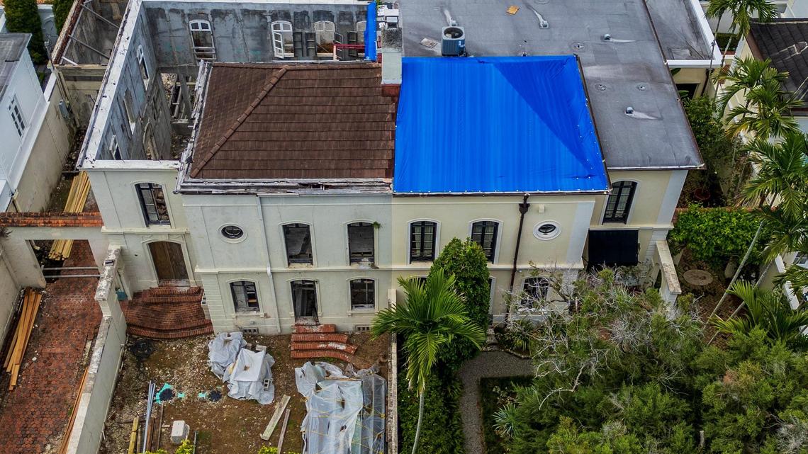 An aerial view of a landmark 1925 home in Coral Gables’ historic French City Village that is in danger of collapsing after years of neglect by its owners, at left, shows a missing roof and gutted interior. The house’s hazardous condition has caused extensive damage to the roof and walls of the attached home on the right, which is still occupied.