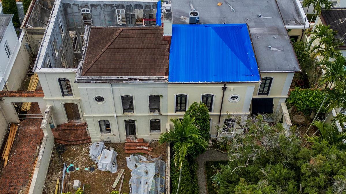 An aerial view of a landmark 1925 home in Coral Gables’ historic French City Village that is in danger of collapsing after years of neglect by its owners, at left, shows a missing roof and gutted interior. The house’s hazardous condition has caused extensive damage to the roof and walls of the attached home on the right, which is still occupied.