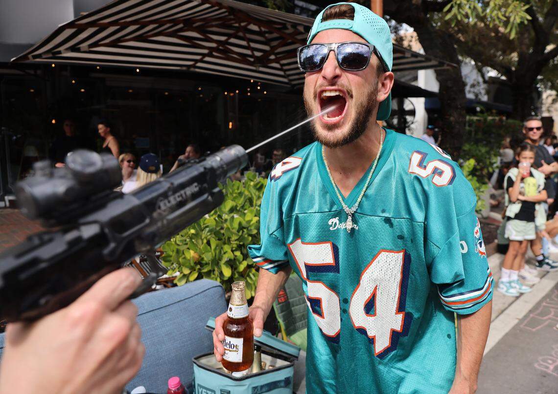 Edward Cinque, right, visiting from Vermont, get shot from Barracuda owner Lee Kassel prior to the start of the 42nd Annual King Mango Strut on Sunday, January 4, 2026, in the heart of the Grove in Miami, Florida.