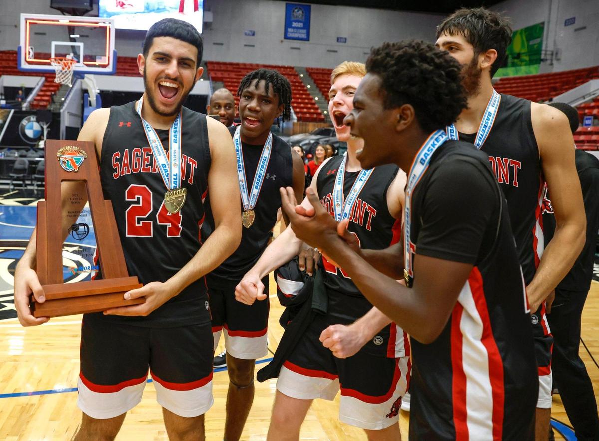 Sagemont High School’s Dominic Issa (24) holds the State Championship Trophy as he celebrates with teammates after defeating Orlando Christian Prep in the FHSAA Class 2A Final at the RP Funding Center in Lakeland, Florida on Friday, March 3, 2023.