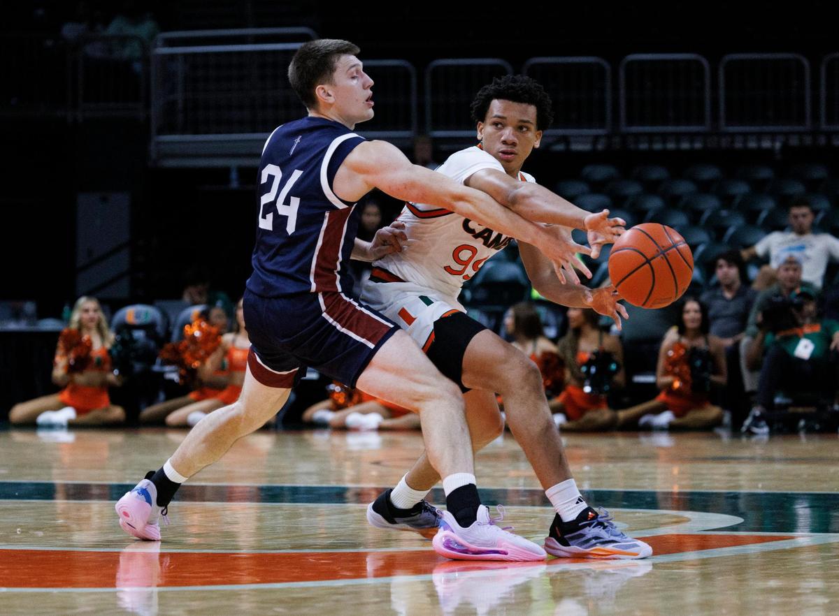Miami Hurricanes Divine Ugochukwu (99) passes the ball around Fairleigh Dickinson Knights Brayden Reynolds (24) during the second half of the season opener game on Monday, Nov. 4, 2024, at Watsco Center in Coral Gables, Fla. The Miami Hurricanes won.