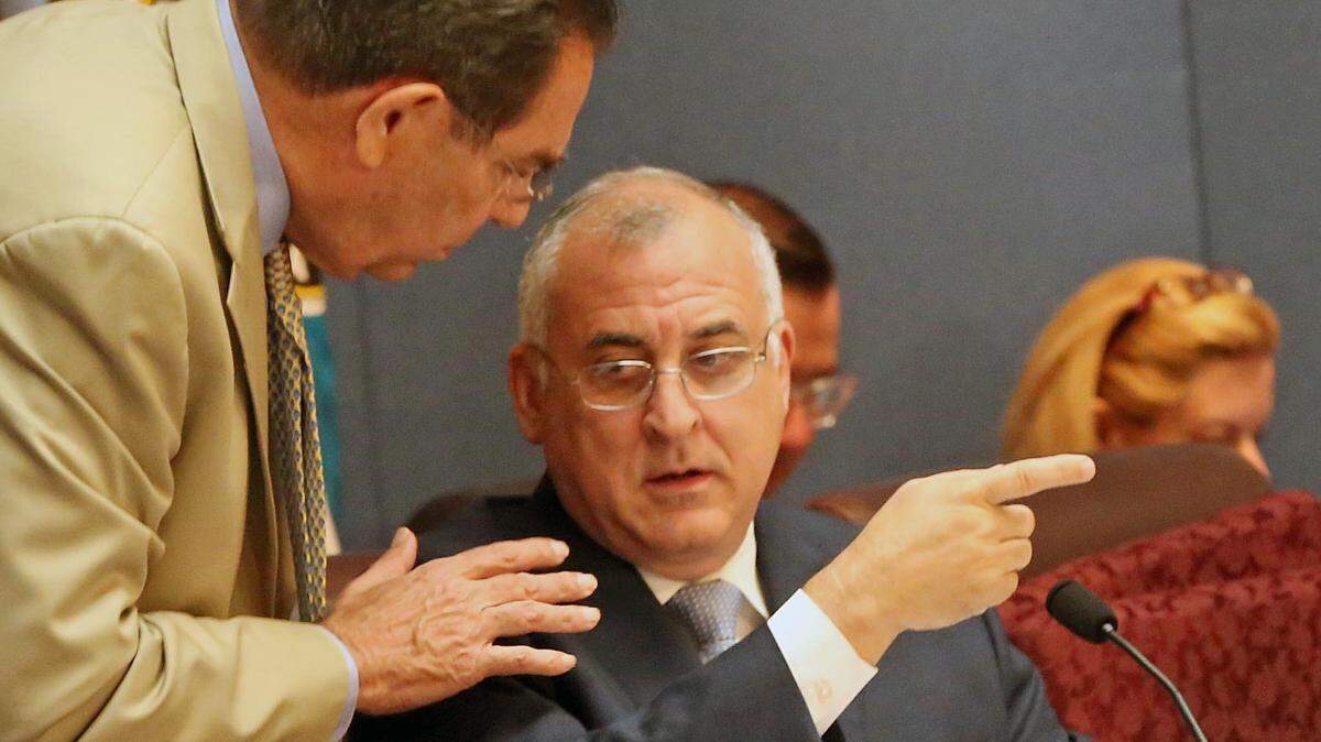 According to law enforcement sources, one of two teens shot and injured during a robbery attempt in Southwest Miami-Dade on Monday is the nephew of Miami-Dade County Commissioner Esteban “Steve” Bovo, seen talking to County Commissioner Xavier Suarez, left, during a May 2018 meeting.
