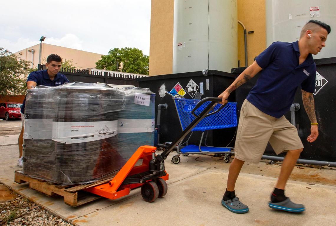 Pinch A Penny employees Amaury Alejo, right, and Julio Villamar move delivered chemicals to the retail pool supply and service company at 11035 Bird Road in Miami on Saturday, Nov. 13, 2021.