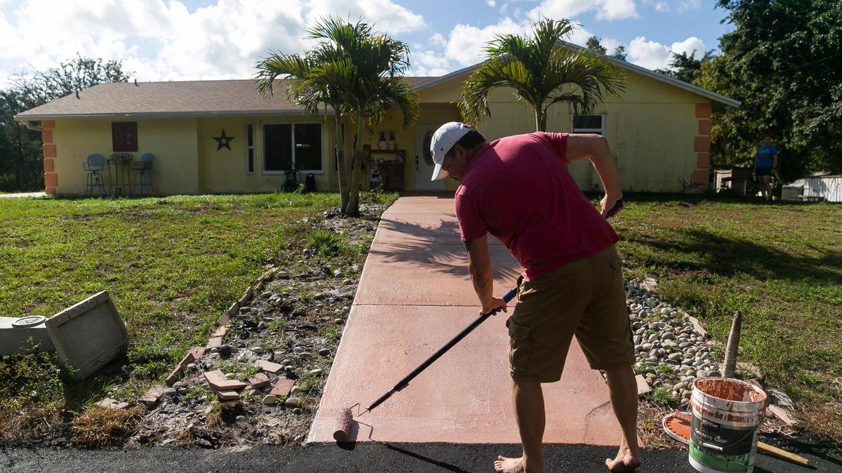 Ray Coulter, de 53 años, pintando su rampa delantera el miércoles 31 de enero de 2023, en West Palm Beach, Florida. Coulter y su esposa, Kelly Coulter, usaron la financiación Ygrene para financiar un nuevo techo y ventanas de impacto antes que Ygrene retirara la financiación para todos en la Florida.