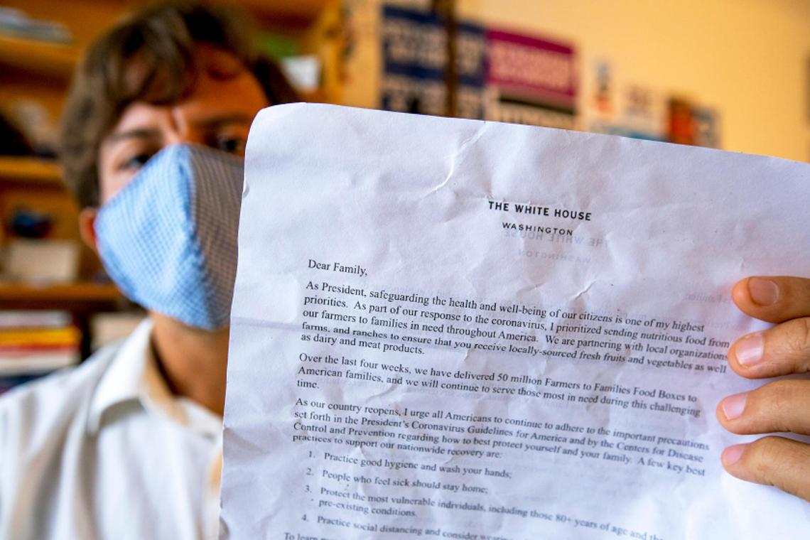 Matthew Luis Killen, 36, holds up the letter from President Donald Trump that he received in food boxes this month from the latest round of the U.S. Department of Agriculture’s Farmers to Families Food Box Program as it reached Miami Beach, Florida, on Friday, Oct. 2, 2020.