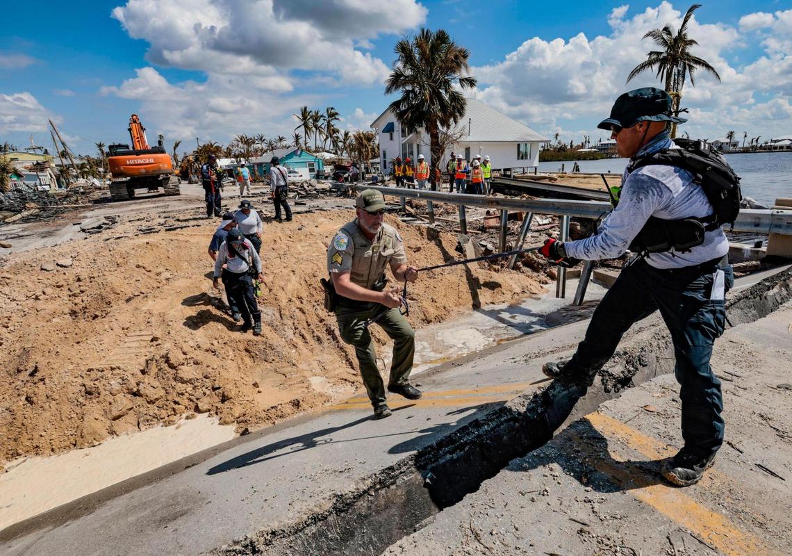 Charles Brodbeck, rescue specialist for Urban Search and Rescue Florida Task Force 1, assists Sgt. John Parsons with the Department of Agriculture and Consumer Services climb the Matlacha bridge damaged during Hurricane Ian, Tuesday, October 4, 2022.