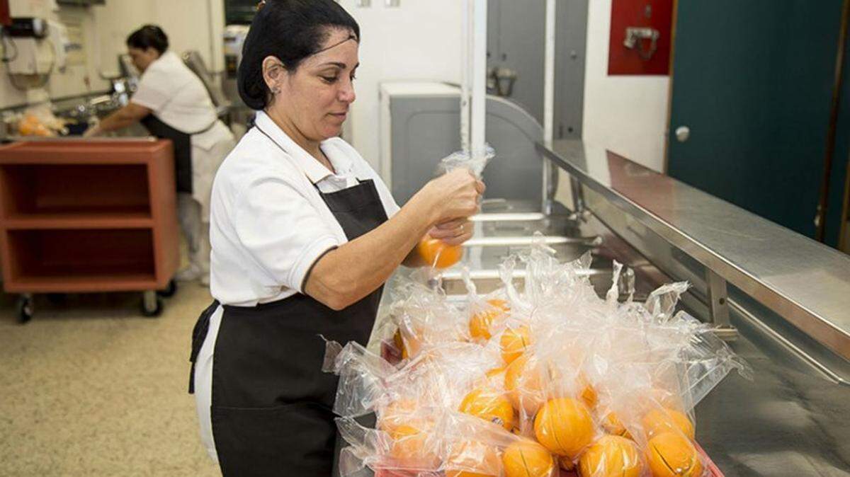 A cafeteria worker preps oranges for students.