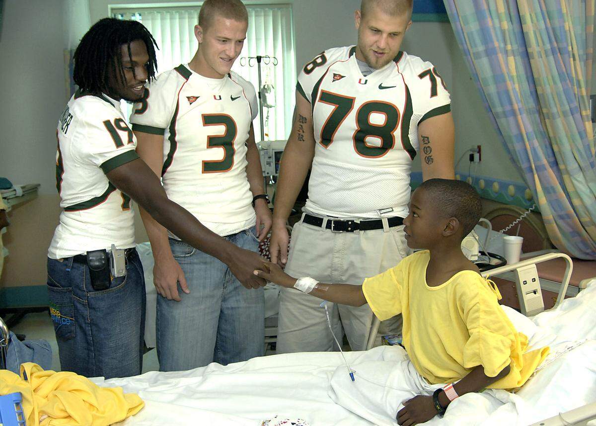 10/13/06 -- Brandon Meriweather, Kyle Wright and Anthony Wollschlager say “hi” to Brian Panton, 10 years old. Edgar Estrada/Courtesy of the University of Miami