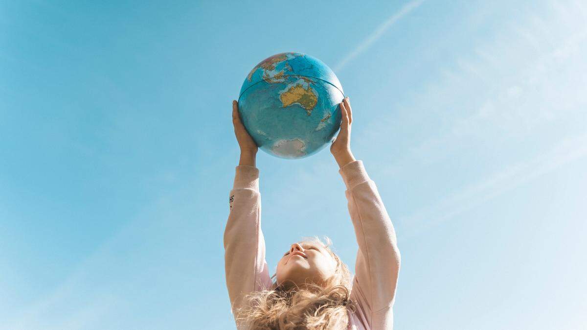 young girl holding globe to the sky