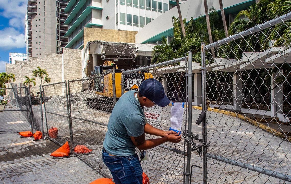 Miami-Dade County pollution inspector Tadeo Monterubias posts a violation notice in front of the historic Deauville Beach Resort in Miami Beach after complaints about dust amid demolition work at the building on Sunday March 13, 2022,