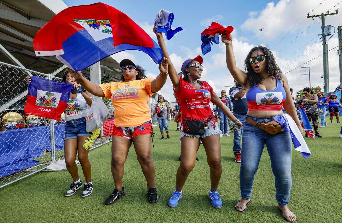 Niah Carr, Kim Carr, Brina Lewis, Erica Lewis dance as they wave Haitian flags while performers sing on stage during the 28th Annual Haitian Compas Festival at The NoMI Village celebrating Haitian Flag Day, in North Miami, Florida  on Saturday, May 16, 2026.