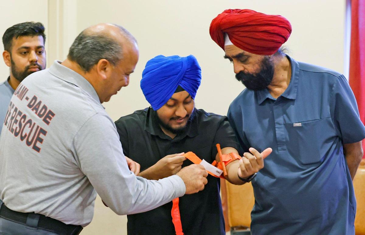 Miami-Dade Fire Rescue Lt. Eddie Ballester demonstrates how to use a tourniquet on Summit Gulati and his father Manjit Gulati, center.