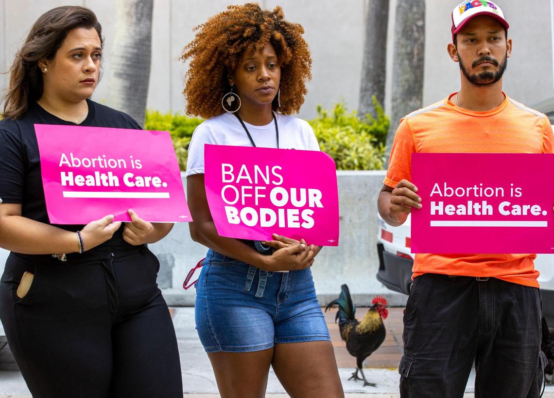 Planned Parenthood’s Miami-Dade regional organizer, Jessica Merino, left, holistic doula Nicky Dawkins, center, and local activist Libre hold protest signs during a Florida Planned Parenthood PAC press conference at Stephen P. Clark Government Center in Miami on Friday, June 24, 2022. The press conference was in response to the U.S. Supreme Court’s overturning the landmark abortion rights decision known as Roe v. Wade.