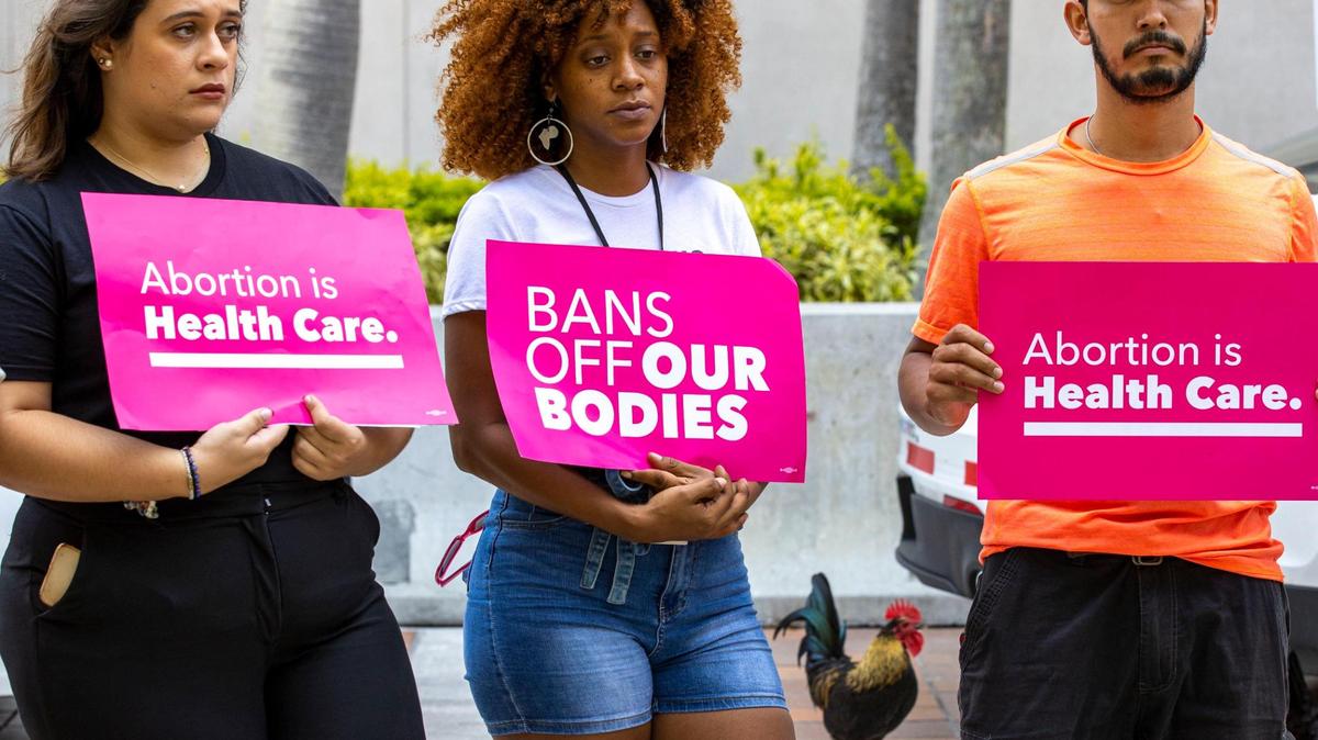 Planned Parenthood’s Miami-Dade regional organizer, Jessica Merino, left, holistic doula Nicky Dawkins, center, and local activist, Libre, hold protest signs during a Florida Planned Parenthood PAC press conference at Stephen P. Clark Government Center in Miami on June 24.