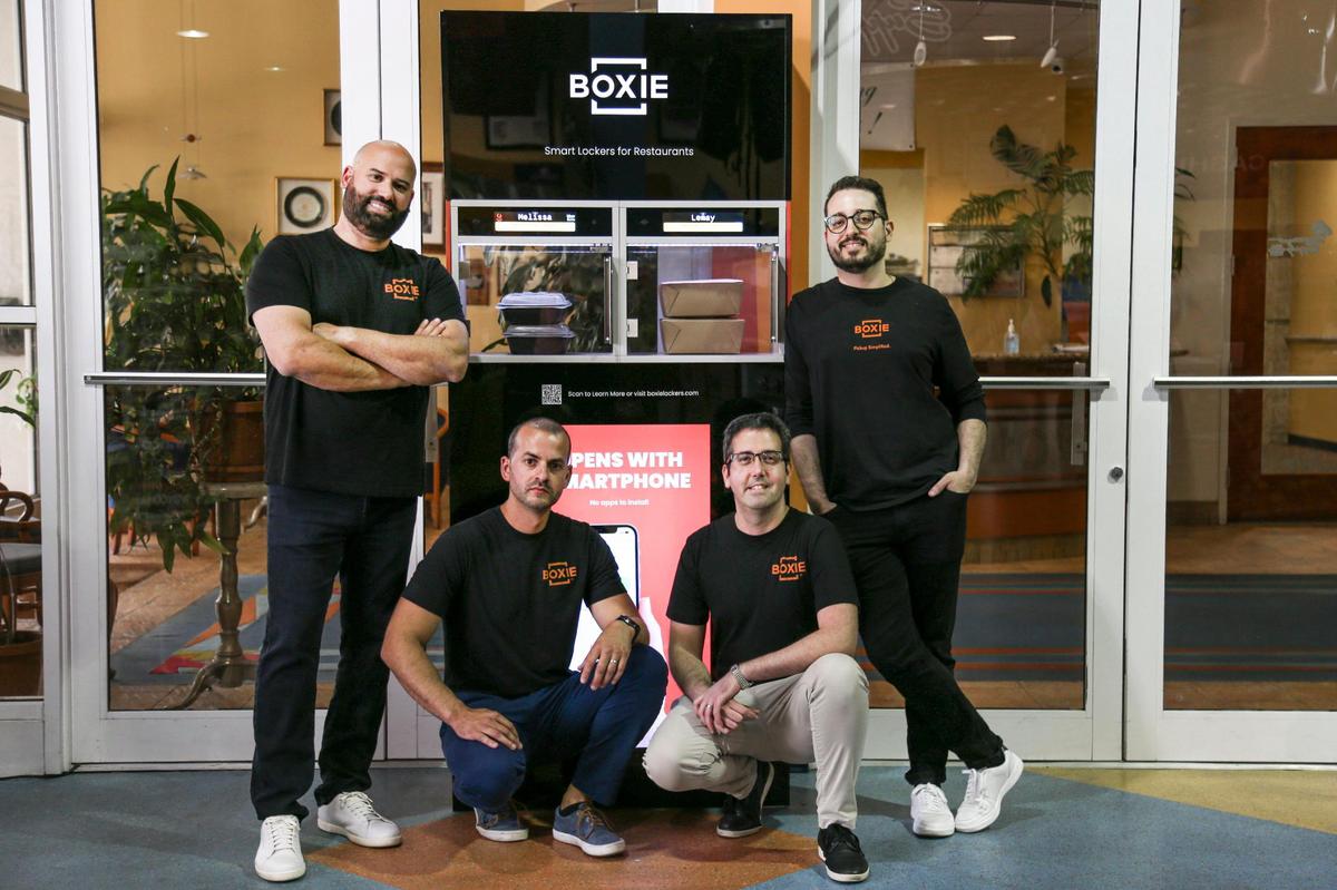 From left: Boxie CEO Lemay Sanchez, lead of mechanical engineering Pedro Machin, lead of embedded systems Daniel Galano, and lead of cloud engineering Arian Acosta are photographed in front of a smart locker at their Hialeah showroom inside General Hotel and Restaurant Supply at 13900 NW 82nd Ave., on Thursday, April 28, 2022. Boxie produces smart lockers for sorting and managing restaurant delivery orders.