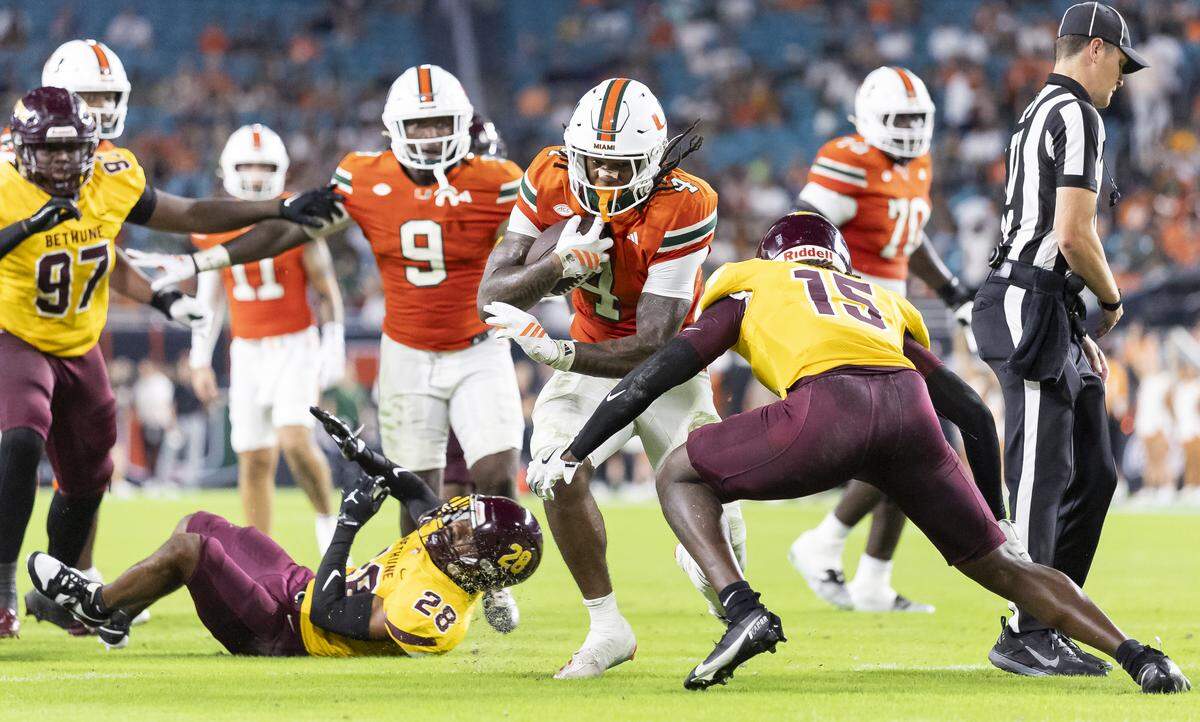 Miami Hurricanes running back Mark Fletcher Jr. (4) runs with the ball as Bethune-Cookman Wildcats safety Antwone Watts (15) defends in the first half of their NCAA football game at Hard Rock Stadium on Saturday, Sept. 6, 2025, in Miami Gardens, Fla.