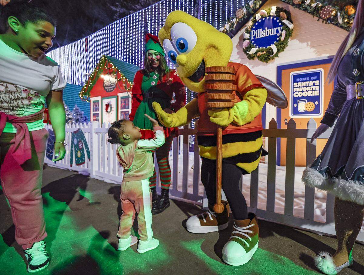 Leah Carrera high fives a Bubble Bee character while visiting Christmas Wonderland at Tropical Park, a Miami-style holiday celebration of flavor and culture in Miami, Florida on Thursday, November 13, 2025.