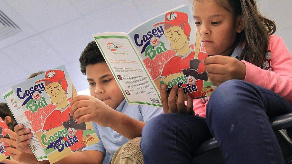 Fourth-graders Miguel Igualas, 10, left, and Diamond Fonseca, 10, right, read along with Marlins outfielder Marcell Ozuna during his visit to their classroom for a bilingual reading session on May 10, 2016, at Kensington Park Elementary School. 
