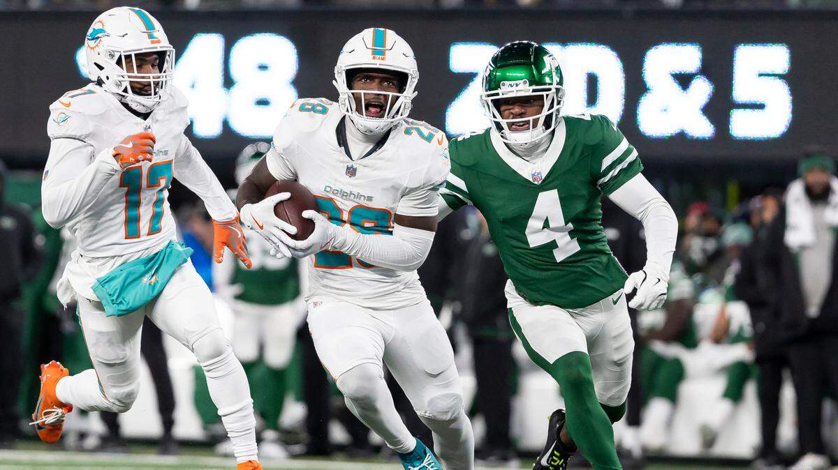 Miami Dolphins running back De’Von Achane (28) runs with the ball as New York Jets cornerback D.J. Reed (4) defends in the first half of their NFL game at MetLife Stadium on Sunday, Jan. 5, 2025, in East Rutherford, N.J.