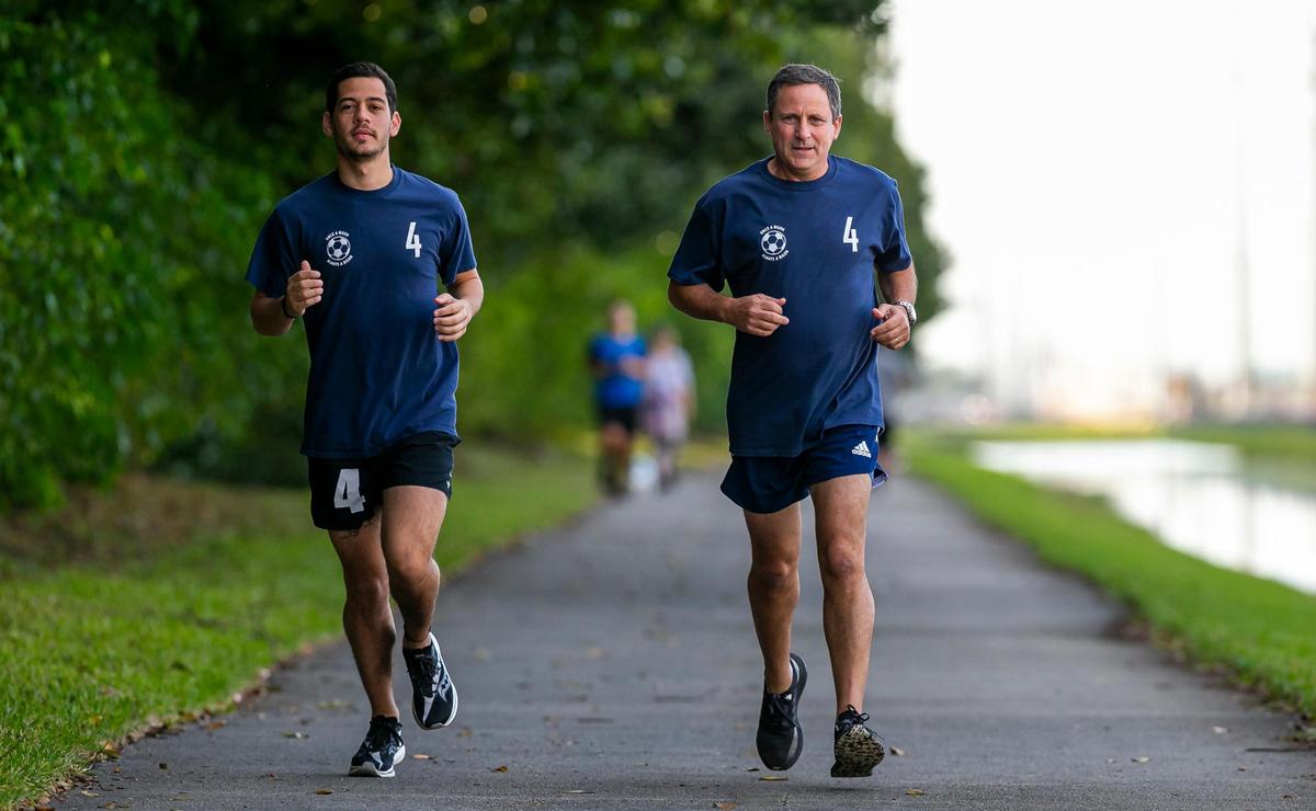 Martin Langesfeld, 24, and his father, Pablo Langesfeld, 56, jog down the Turnpike Trail in Doral, Florida on Wednesday, January 26, 2022. Both Martin and Pablo will be running in the Miami Marathon in honor of Nicole Langesfeld and her husband, Luis Sadovnic, both of whom were killed in the Surfside condominium collapse.