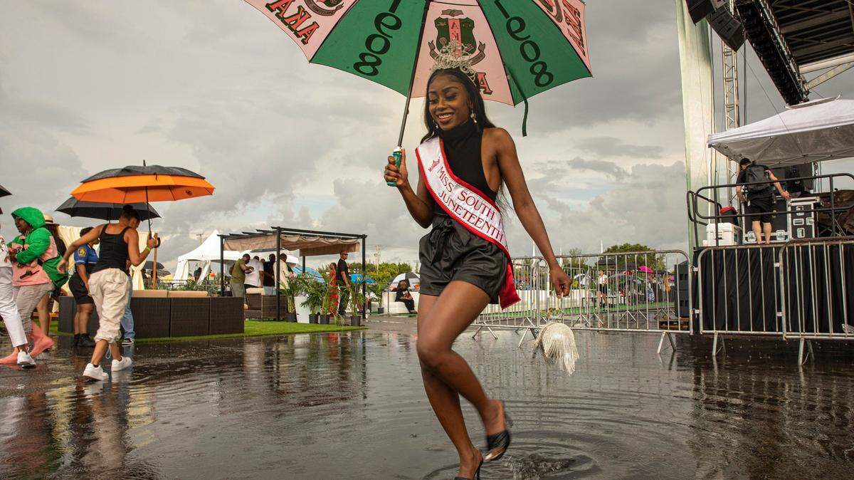 Sklouchere Pierre, Miss South Florida Juneteenth, walks through a puddle after posing for portraits at the 2nd Annual Juneteenth Park-In and Party Celebration: We Are One in Miami Gardens, Fla. on Sunday, June 19, 2022.