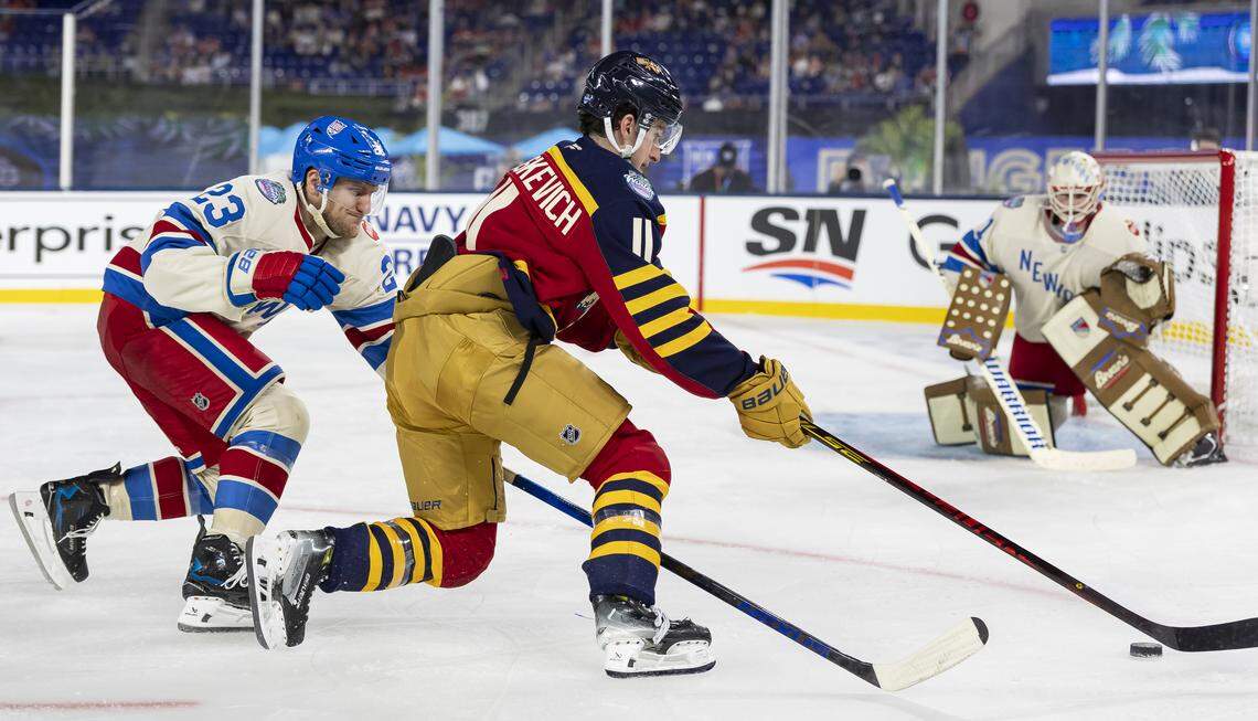 Florida Panthers right wing Mackie Samoskevich (11) skates with the puck as New York Rangers defenseman Adam Fox (23) defends in the third period of their Winter Classic outdoor hockey game at loanDepot park on Friday, Jan. 2, 2026, in Miami, Fla.