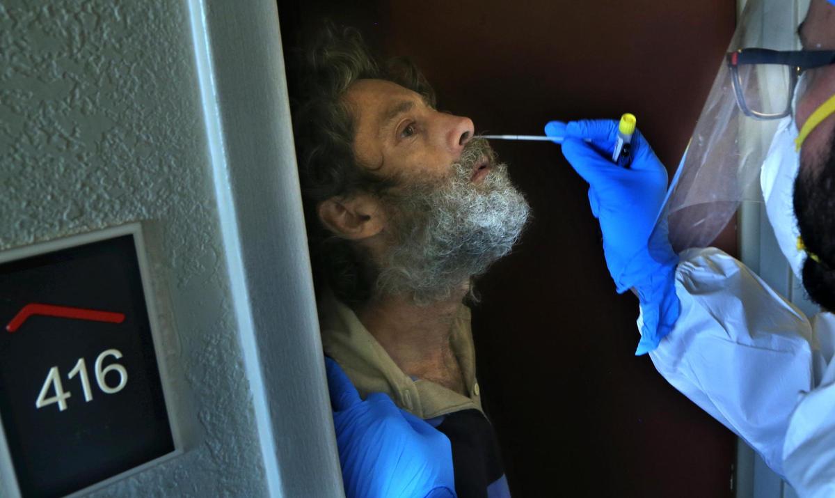 Camillus House Medical staff RN Pavel Suarez, does a covid-19 test to Gustavo Fernandez, a man part of a group of mostly homeless people sheltered by Camillus House at a Miami hotel as the Covid-19 positives cases surge in Miami-Dade County different organizations like the Homeless Trust are working to avoid a surge of the virus among the homeless population. on Tuesday, August 14, 2020